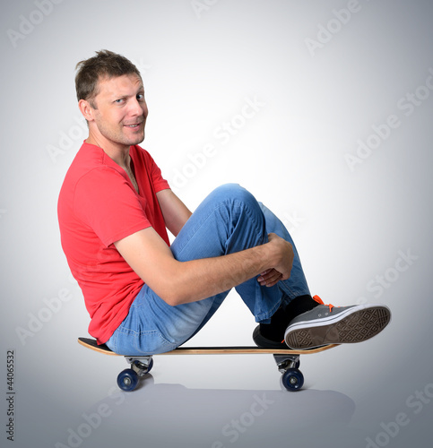 Photo: Cool man sitting on a skateboard deck Cool man sitting on a skateboard deck