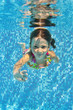 Happy smiling underwater child in swimming pool, summer vacation