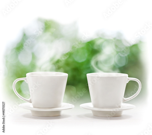 Photo: Cups of hot drink on defocus summer background Cups of hot drink on defocus summer background
