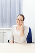 Freundliche Dame mit Handy am Ohr im Büro