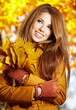 Beautiful elegant woman standing in a park in autumn