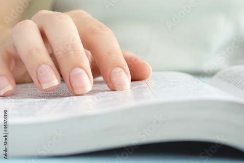 Photo: girl reading a book, shows a close-up hand and a book girl reading a book, shows a close-up hand and a book