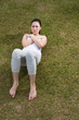 Chinese woman doing sit ups on grass.