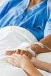 Patient hand with saline intravenous (iv) on hospital bed