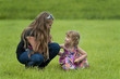 Happy teenage girl and a toddler in the grass