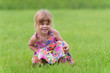 Photo: Happy little girl sitting in the grass Happy little girl sitting in the grass
