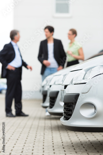 Photo: Autohändler und Kunden schauen ein Auto an Autohändler und Kunden schauen ein Auto an