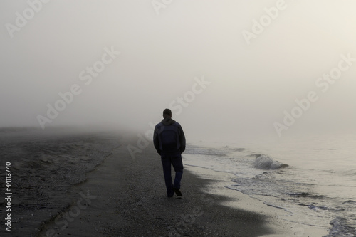 Photo: Lonely man walking on a beach Lonely man walking on a beach
