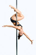 Young sexy woman exercise pole dance against a gray background