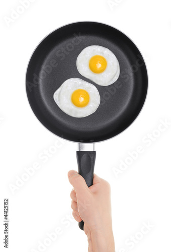 Photo: Fried eggs on the pan. Pan in hand on white background. Fried eggs on the pan. Pan in hand on white background.