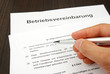 Betriebsvereinbarung mit Hand und Kugelschreiber