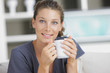 Close-up of a young woman smiling and drinking coffee
