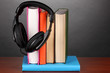 Headphones on books on wooden table on black background
