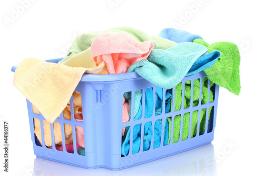 Photo: Plastic basket with bright towels isolated on white Plastic basket with bright towels isolated on white