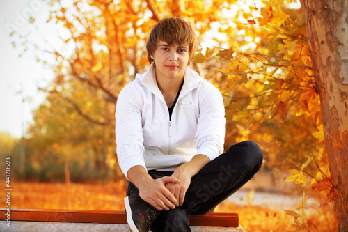 Photo: Young man sitting on the bench, autumn Young man sitting on the bench, autumn