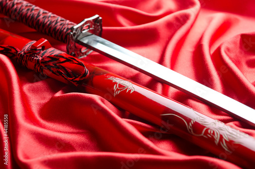 Photo: Japanese sword takana on red satin background Japanese sword takana on red satin background