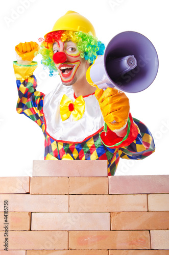 Photo: Bad construction concept with clown laying bricks Bad construction concept with clown laying bricks