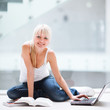 Foto : On campus - pretty female student with laptop and books working On campus - pretty female student with laptop and books working