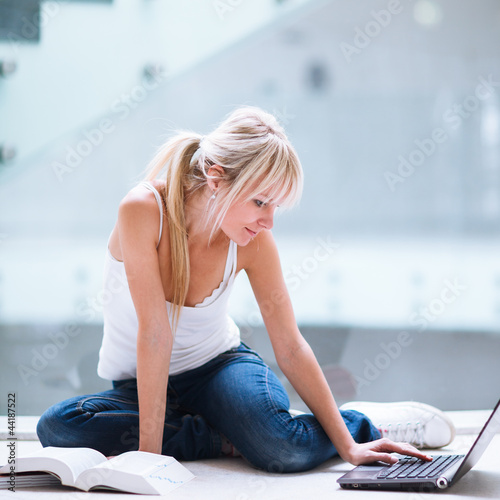 Foto : On campus - pretty female student with laptop and books working On campus - pretty female student with laptop and books working