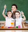 Little pupils study chemistry with their attractive teacher
