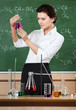 Smiley chemistry teacher examines conical flask with pink liquid