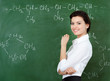 Smiley teacher hands chalk standing at the blackboard