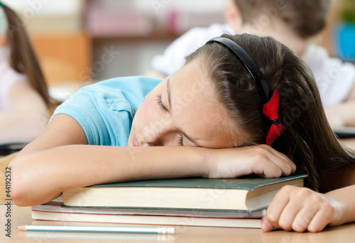 Foto: Tired schoolgirl sleeps at the desk, close up Tired schoolgirl sleeps at the desk, close up