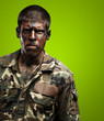 young soldier with camouflage paint looking very serious over gr