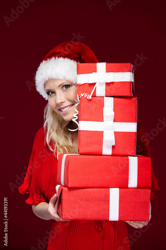 Photo: Attractive girl in Christmas cap hands a set of presents Attractive girl in Christmas cap hands a set of presents