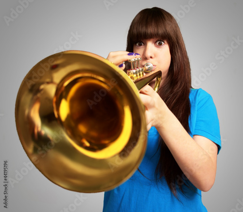 Photo: portrait of a young girl blowing trumpet portrait of a young girl blowing trumpet