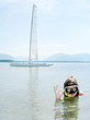 Young girl snorkeling in sea against her sail boat.