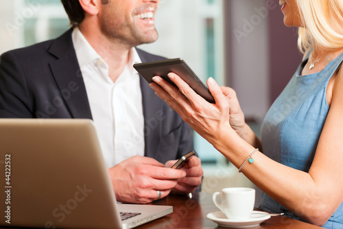 Photo: Working colleagues - man and woman - sitting in cafe Working colleagues - man and woman - sitting in cafe