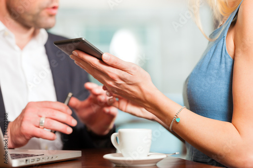 Photo: Working colleagues - man and woman - sitting in cafe Working colleagues - man and woman - sitting in cafe