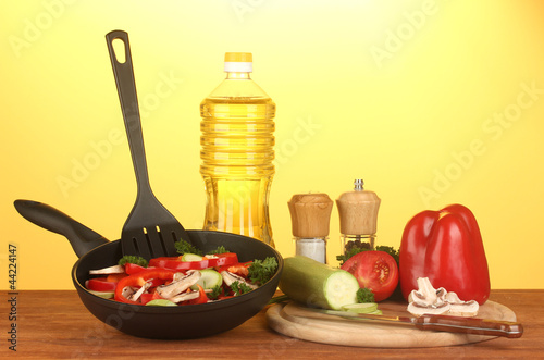 Foto: frying pan with vegetables on yellow background frying pan with vegetables on yellow background