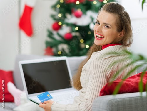 Photo: Smiling young woman making Christmas shopping on internet Smiling young woman making Christmas shopping on internet