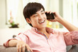 Photo: Young Chinese Man Using Mobile Phone On Sofa At Home Young Chinese Man Using Mobile Phone On Sofa At Home