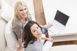 Two Young Women Using Laptop Computer At Home on Sofa