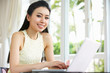 Young Chinese Woman Sitting At Desk Using Laptop At Home