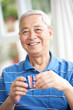 Senior Chinese Man Drinking Tea On Sofa At Home