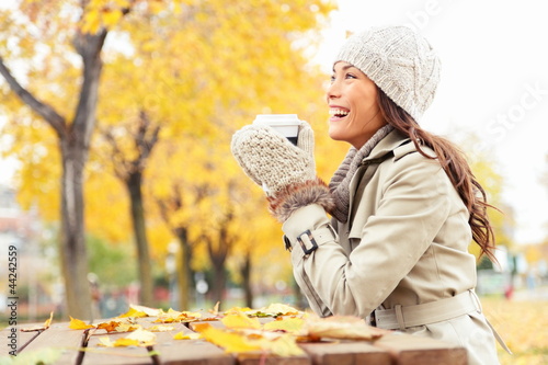 Photo: Fall concept - autumn woman drinking coffee in park Fall concept - autumn woman drinking coffee in park