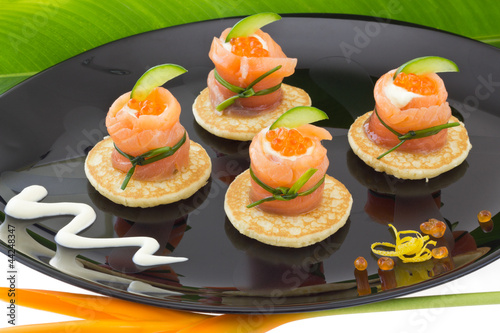 Photo: Red salmon roll with cheese, caviar and cucumber on” blinis” Red salmon roll with cheese, caviar and cucumber on” blinis”