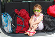 a little girl  sitting in the car with backpacks