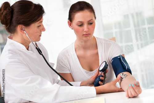 Photo: Ärztin misst den Blutdruck und Puls bei Patientin Ärztin misst den Blutdruck und Puls bei Patientin