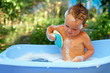 baby boy washes with sponge in bubble bath outdoor