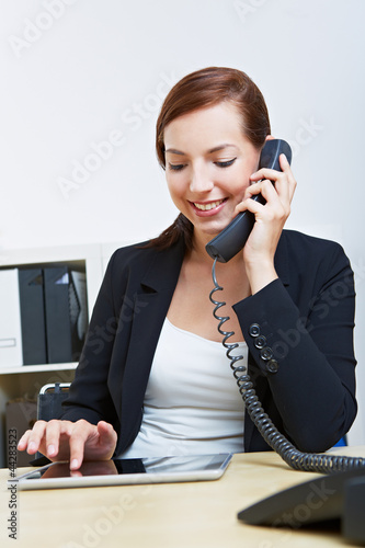 Photo: Frau im Büro telefoniert neben Tablet Computer Frau im Büro telefoniert neben Tablet Computer
