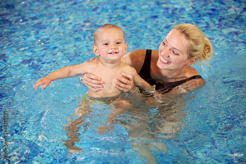 Photo: Young mother and little son having fun in a swimming pool Young mother and little son having fun in a swimming pool
