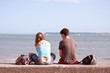 two teenagers sat on beach wall together