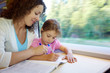 Mother and daughter draw in colour magazine, sitting in armchair