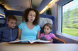 Mother reads book to her children, sitting in armchair of coach