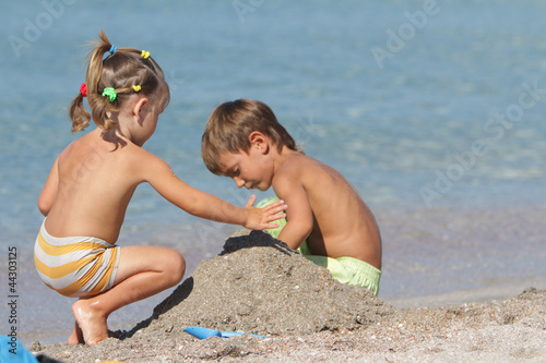 Photo: outdoor portrait of two children playing on sand beach outdoor portrait of two children playing on sand beach